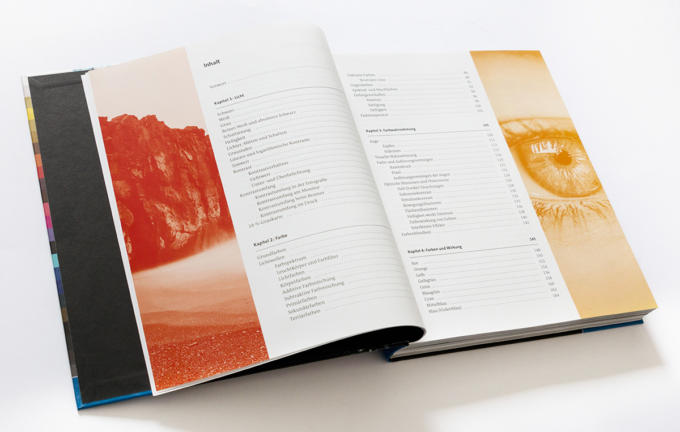 Aufgeschlagenes Buch mit dem Motiv „Das ABC der Farbe“: Auf der rechten Seite befindet sich ein Inhaltsverzeichnis mit Kapiteln und Seitenzahlen. Links zeigt eine abstrakte Illustration in Rot und Orange Felsen und Wasser, während die Nahaufnahme eines Auges die rechte Seite ziert.