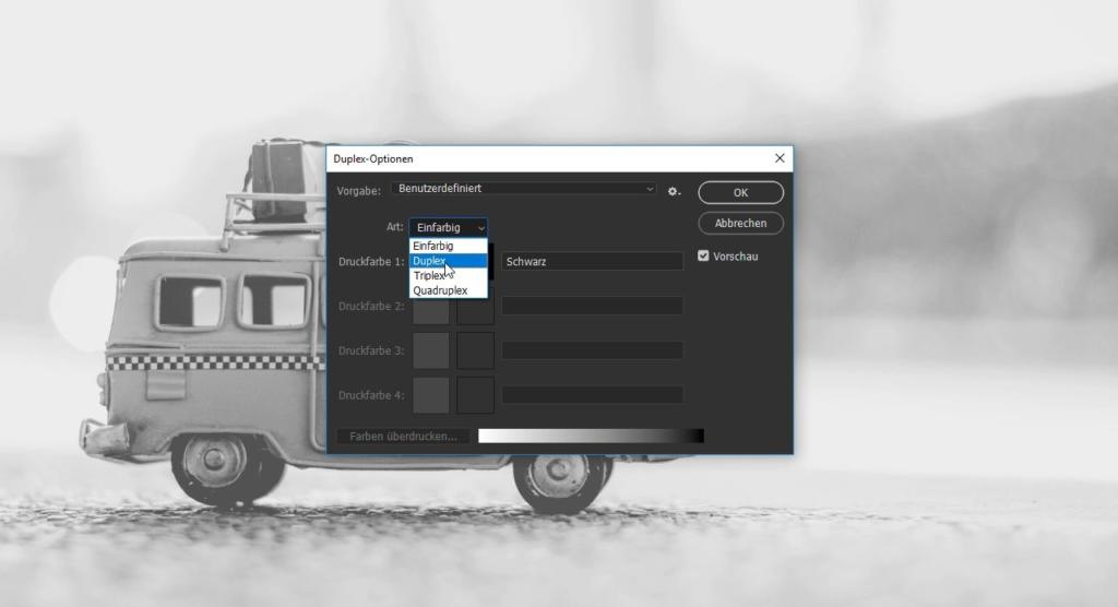 Ein alter Spielzeug-Van steht auf einer Oberfläche, jetzt in Sepiatönen. Ein digitales Fenster öffnet sich und bietet Duplexdruck-Optionen auf Deutsch mit einer eleganten, modernen Benutzeroberfläche. Einstellungen wie „Einfarbig“ und „Duplex“ füllen das Dropdown-Menü, als wären sie von Photoshop-Experten erstellt worden.