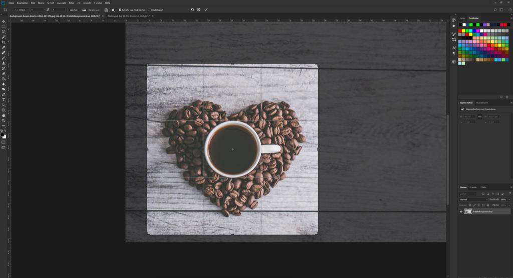 Eine Tasse Kaffee auf einer weißen Holzoberfläche, umgeben von herzförmig angeordneten Kaffeebohnen. Das Bild wird in der Benutzeroberfläche einer Bildbearbeitungssoftware mit sichtbaren Werkzeugen und Ebenen auf dem Bildschirm angezeigt.