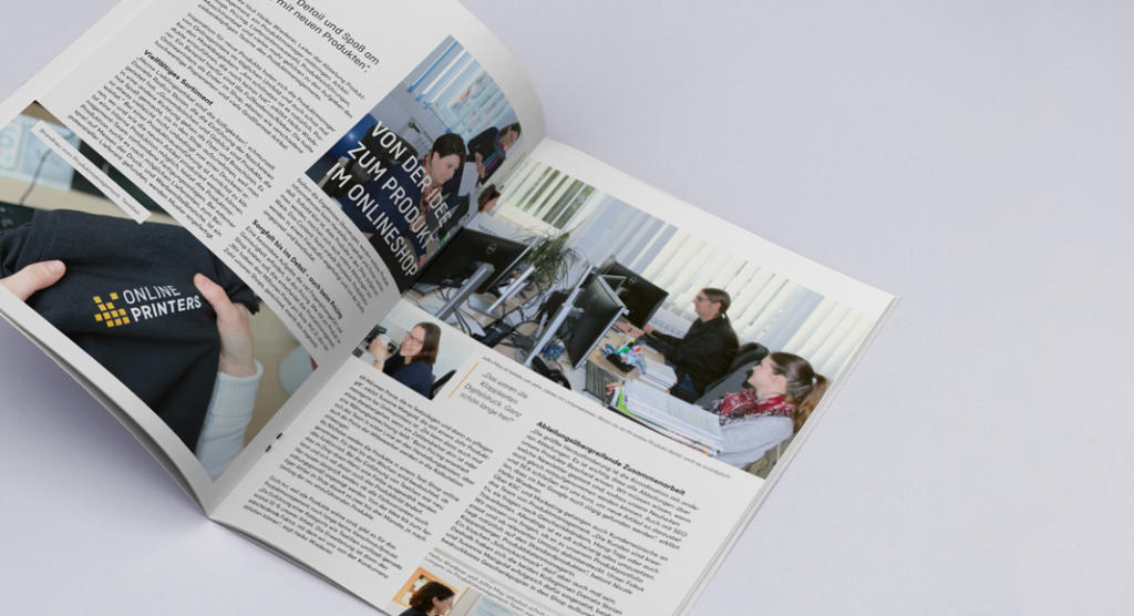 Das aufgeschlagene Magazin präsentiert zwei Seiten. Auf der linken Seite sind ein Artikel mit Text und eine Person mit einem „ONLINE PRINTERS“-Shirt zu sehen. Auf der rechten Seite ist ein Foto von Menschen am Computer zu sehen, ergänzt durch weiteren Text und Bilder, die den dynamischen Charakter einer Mitarbeiterzeitung verkörpern.