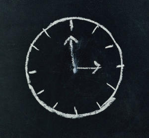 Eine mit weißer Kreide auf eine Tafel gemalte Uhr zeigt ungefähr 10:10 Uhr an. Das Zifferblatt ist schlicht, ähnlich wie zeitlose Strategien im Content-Marketing – klar, effektiv und ohne unnötige Zahlen, die die Botschaft überladen.