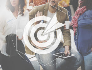 Drei Personen unterhalten sich mit Kaffeetassen in der Hand. Ein Mann in beiger Jacke hält ein Tablet und diskutiert vermutlich Content-Marketing-Strategien. Über der Szene befindet sich eine durchscheinende Zielgrafik mit einem Pfeil in der Mitte, die Fokus und Präzision symbolisiert.