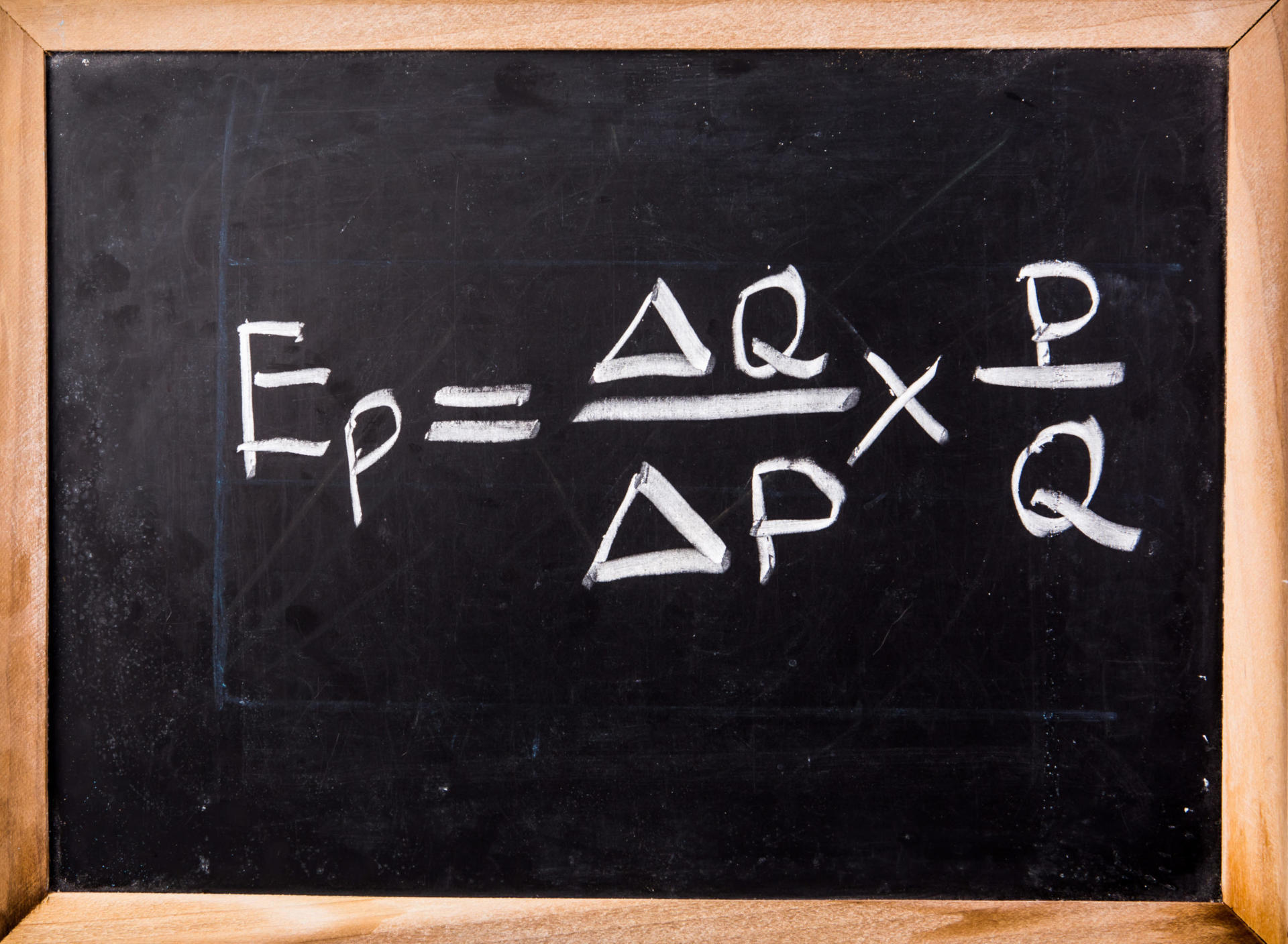 Tafel mit der Formel für die Preiselastizität der Nachfrage: Ep = (ΔQ/ΔP) × (P/Q). Die Gleichung ist elegant mit weißer Kreide auf dunklem Hintergrund geschrieben.