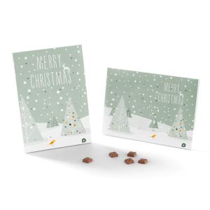 Zwei rechteckige Weihnachtsboxen, perfekt als Weihnachtsgeschenke für Kunden, zeigen schneebedeckte Bäume und den Text „Frohe Weihnachten“. Eine steht aufrecht, die andere liegt flach. Davor liegen kleine Schokoladenstücke, und auf jeder Box ist ein kleiner orangefarbener Vogel abgebildet.