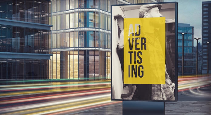 Eine hell erleuchtete Stadtstraße mit einer großen Werbetafel, die eine Person mit Hut auf gelbem Grund zeigt. Das Wort „WERBUNG“ ist vertikal dargestellt. Verschwommene Lichtspuren vorbeifahrender Autos umgeben moderne Glasgebäude.